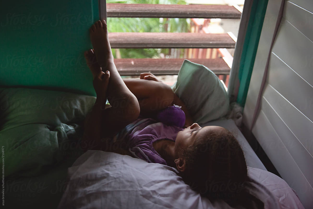 Child lying in bed and looking out of her window
