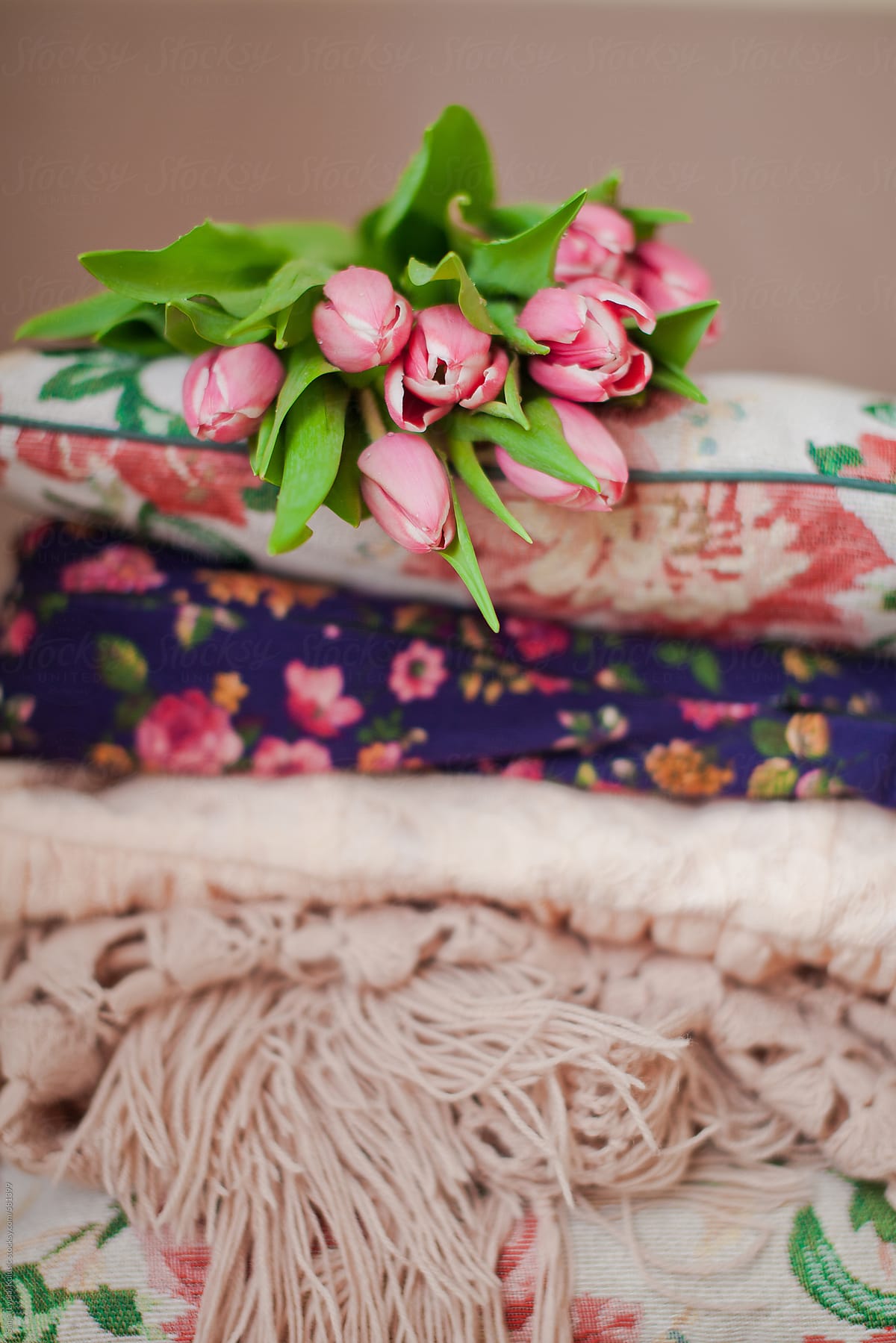 Pile of vintage floral print fabric with fresh cut tulips on top
