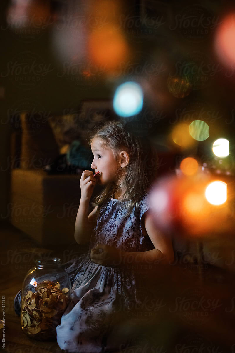 Little girl watching TV by a Christmas tree