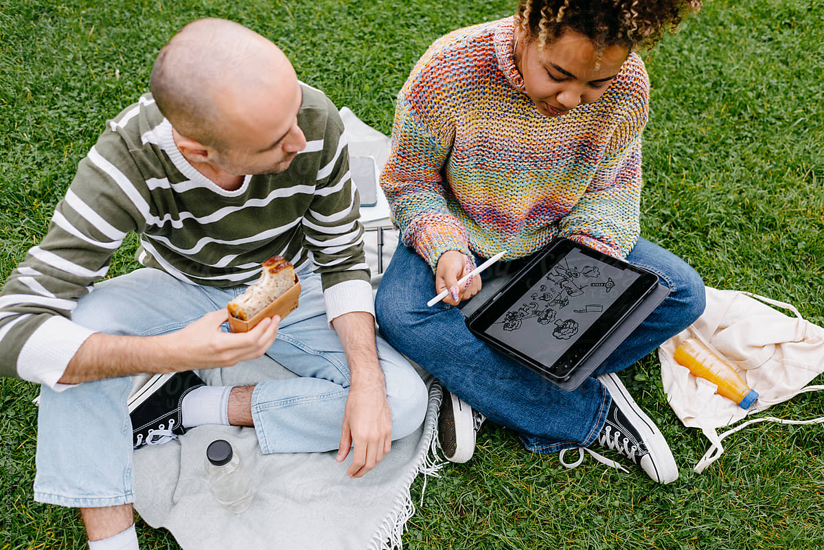 A man and a woman use a tablet outdoors