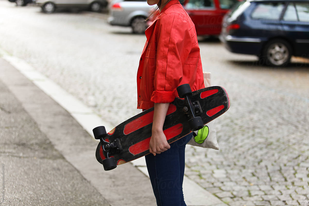Young woman holding a skateboard in the street