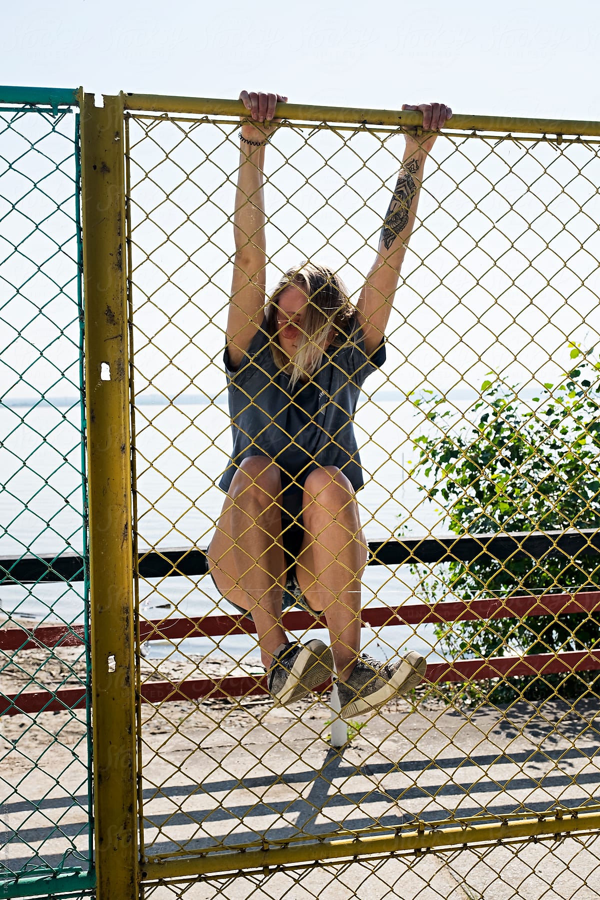 Blonde Wild Girl With Tattoo Climbing The Fence By Stocksy Contributor Danil Nevsky Stocksy