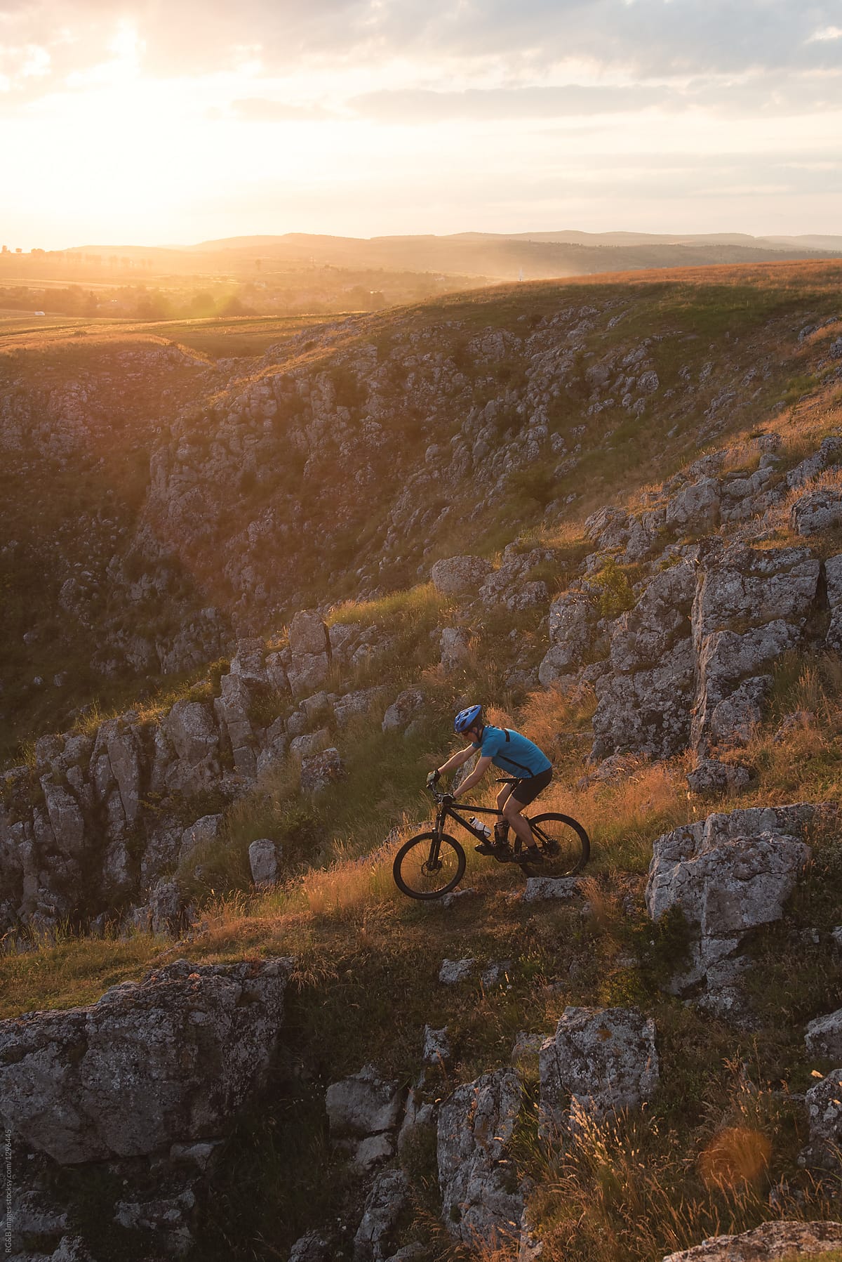 Male biker riding mtb off road in nature during sunset