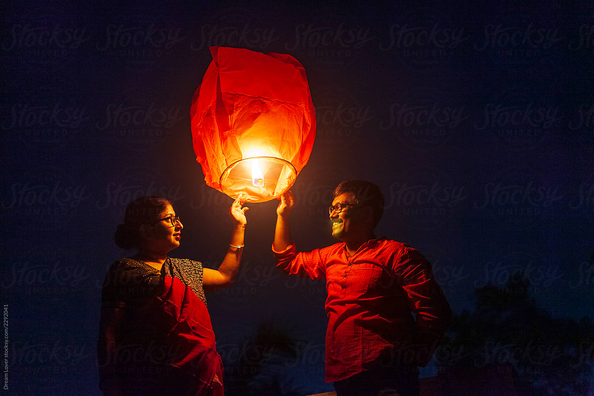 Middle aged couple holding Sky Lantern To The Sky At Twilight