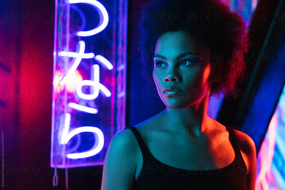 Serious black woman with makeup in neon illumination