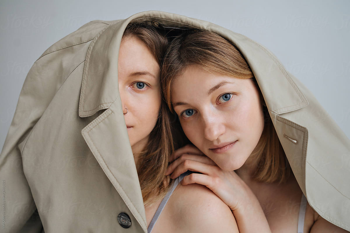 close up of two twin girls under one beige cloak