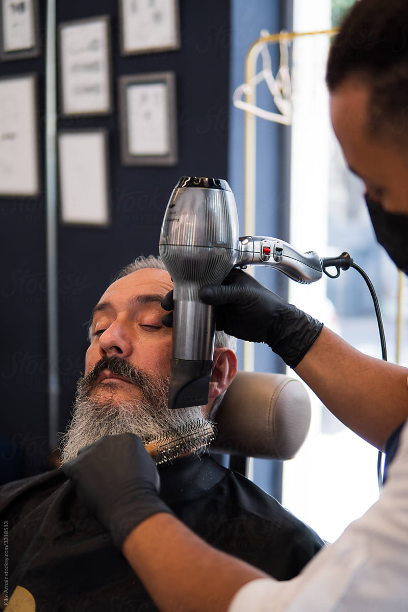 Barber fixing client\'s beard