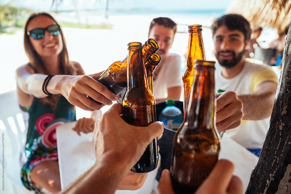Friends toasting their bottles of beer in a beach bar