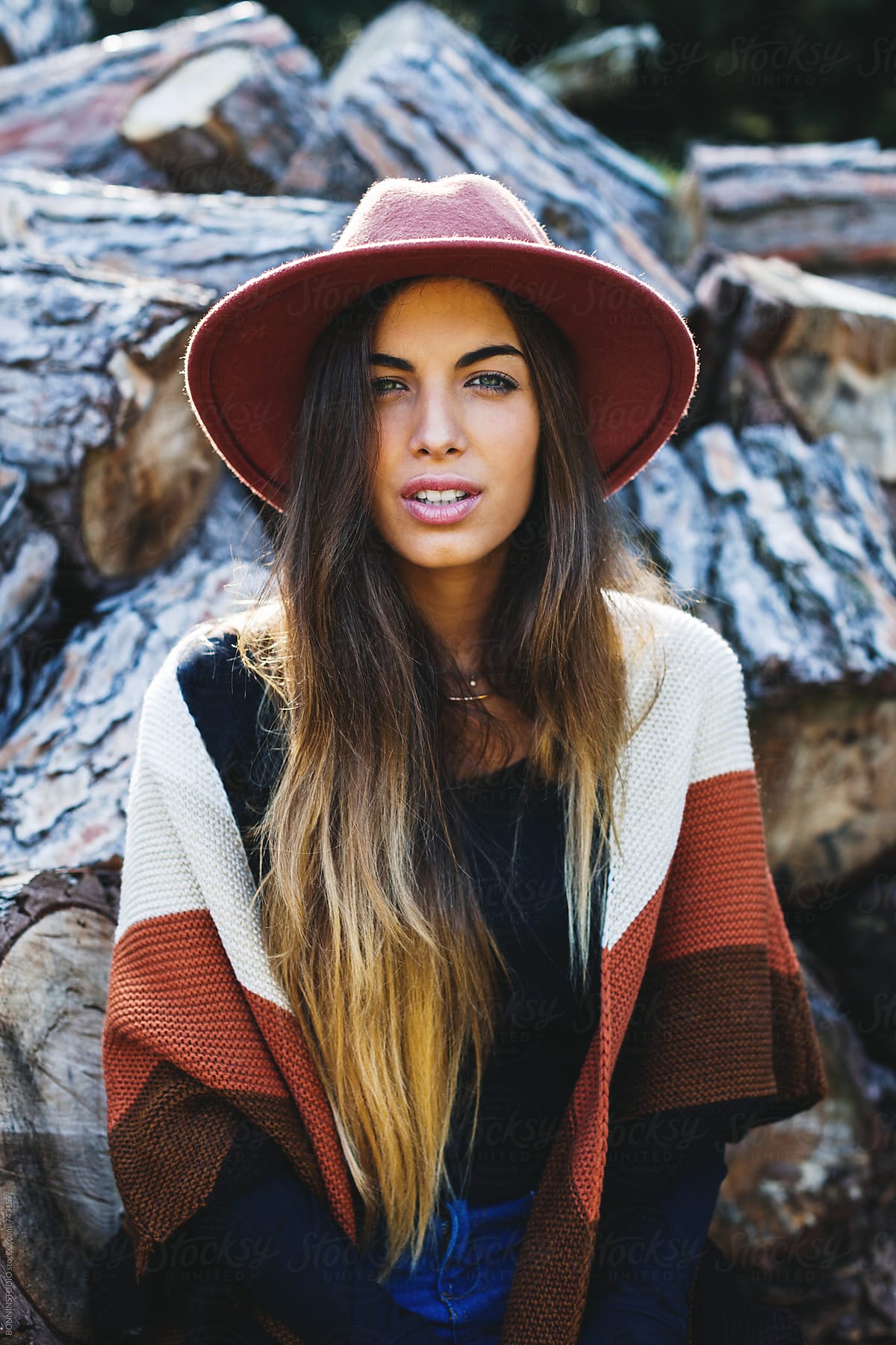 Hipster Woman Sitting In Front Of A Stack Of Trunks. by Stocksy  Contributor BONNINSTUDIO  - Stocksy