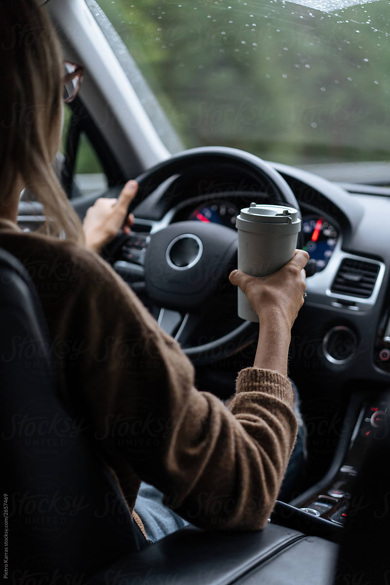 Woman driving car with coffee cup