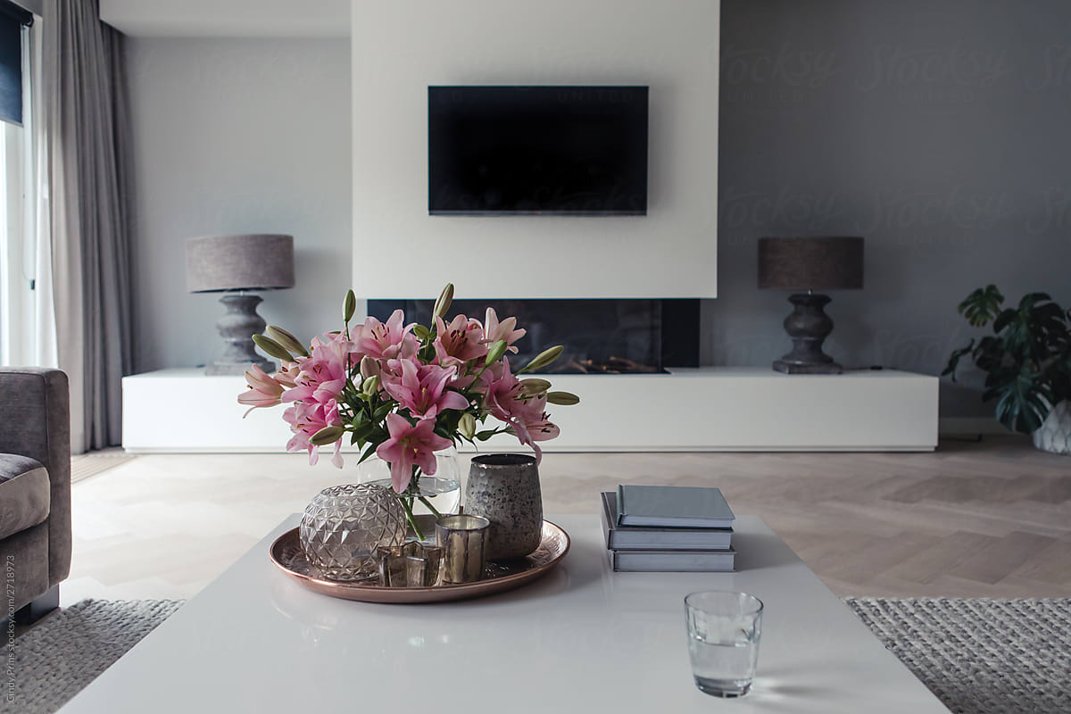 View from the couch of a modern living room with pink lilies on the coffee table