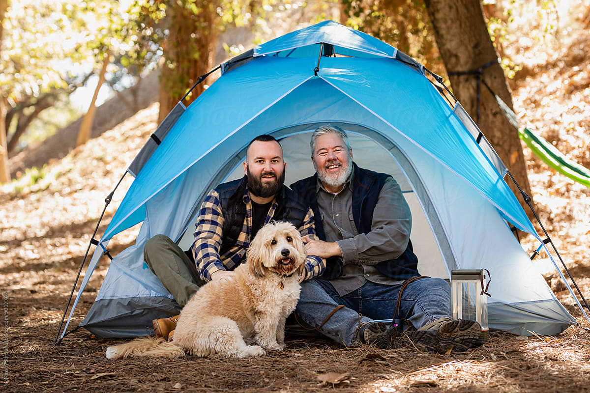 LGBT Couple With Dog Look At Camera While Sitting At Their Tent