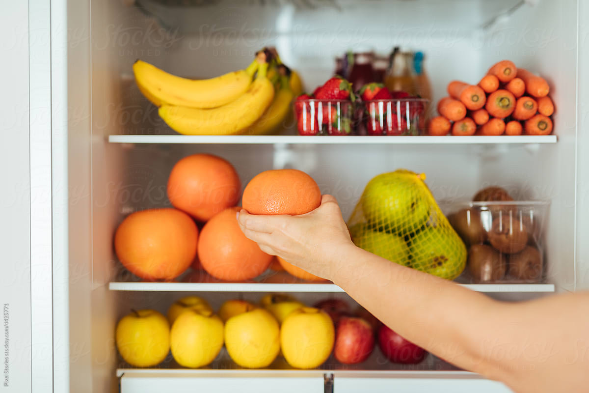 Healthy food concept: Grabbing an orange from fridge
