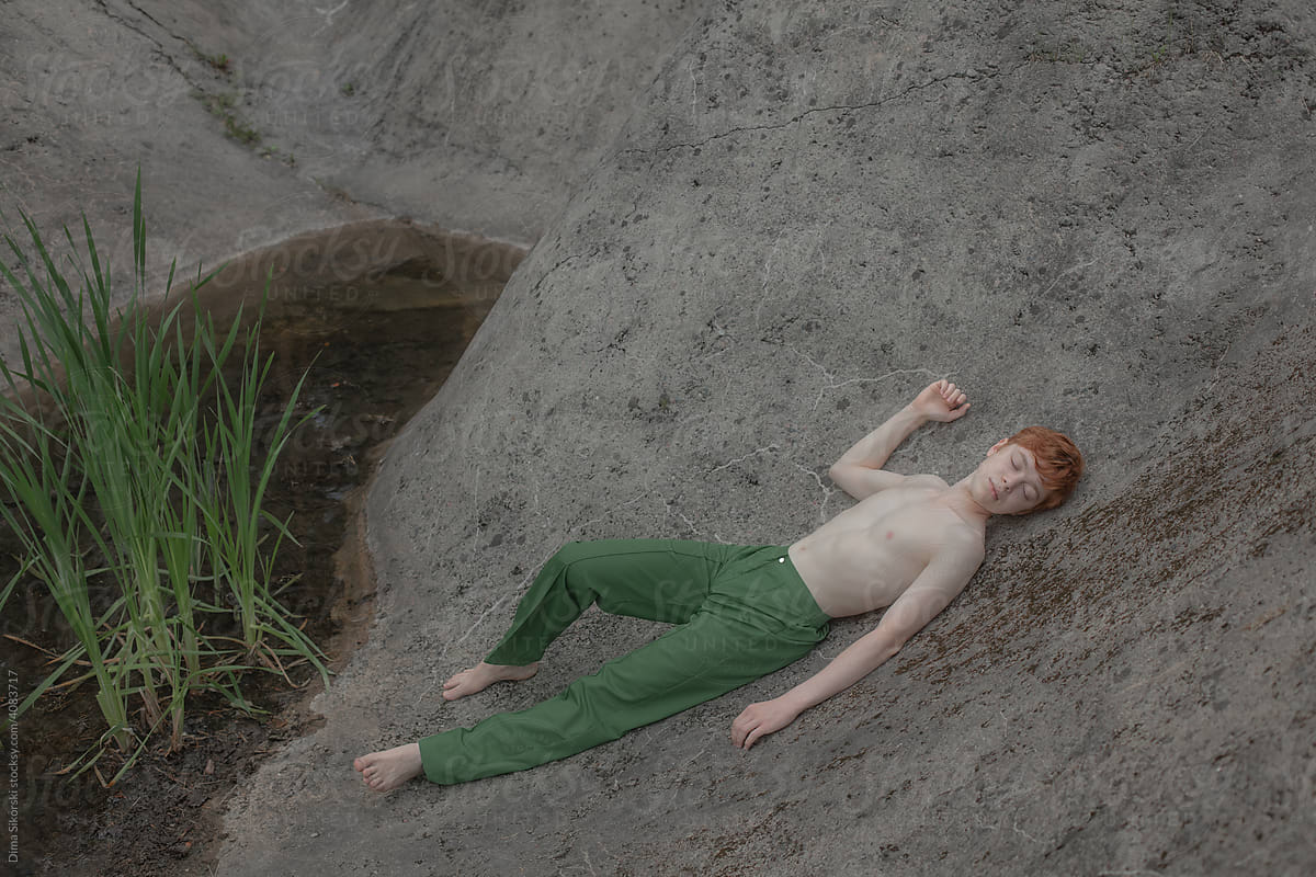 a person is lying relaxed by a pond with vegetation