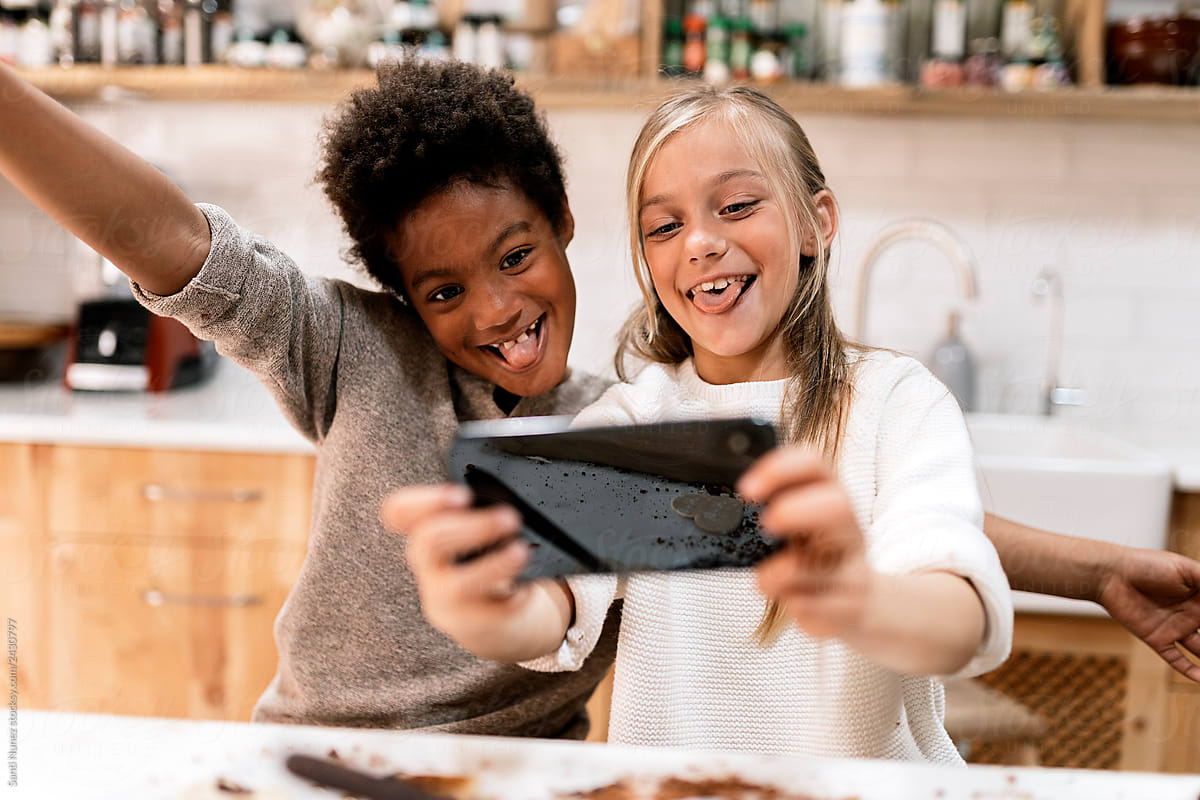 Children making faces with smartphone in kitchen
