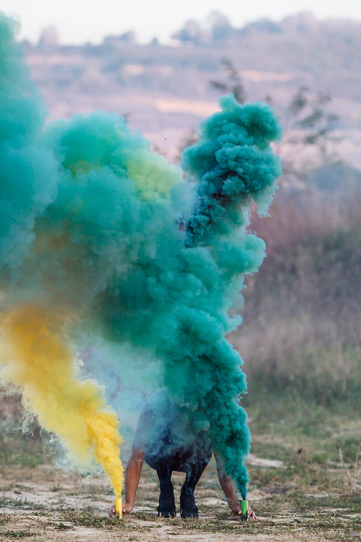 yellow and green,person with two smoke bombs  in nature