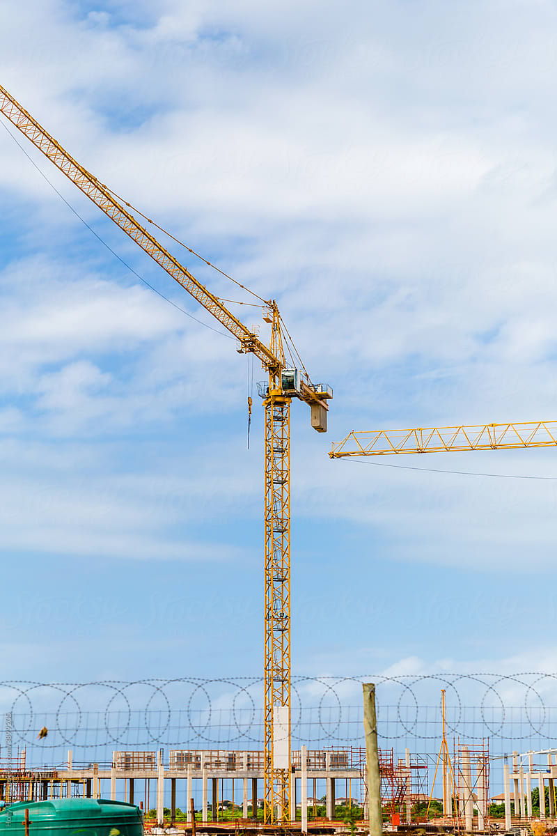 Construction Crane Against Blue Sky Behind Barbed Wire