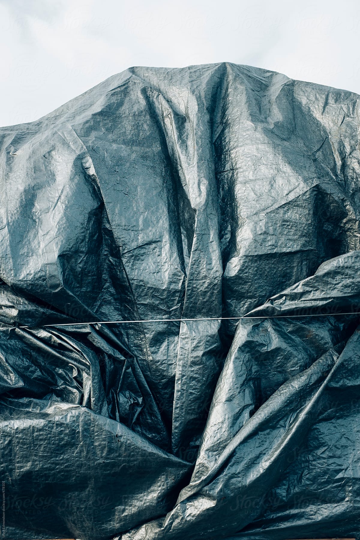 Silver tarpaulin covering pile of commercial fishing equipment
