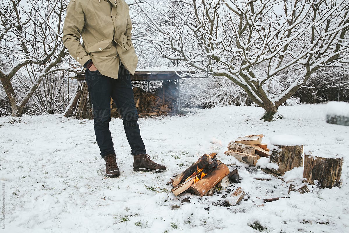 Man relaxing next to a bonfire in the snow
