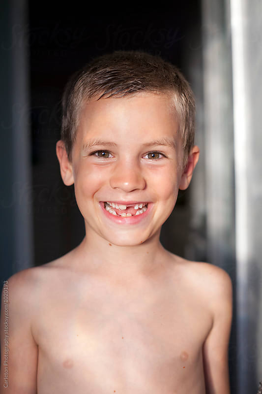 Smiling boy with missing teeth in doorway