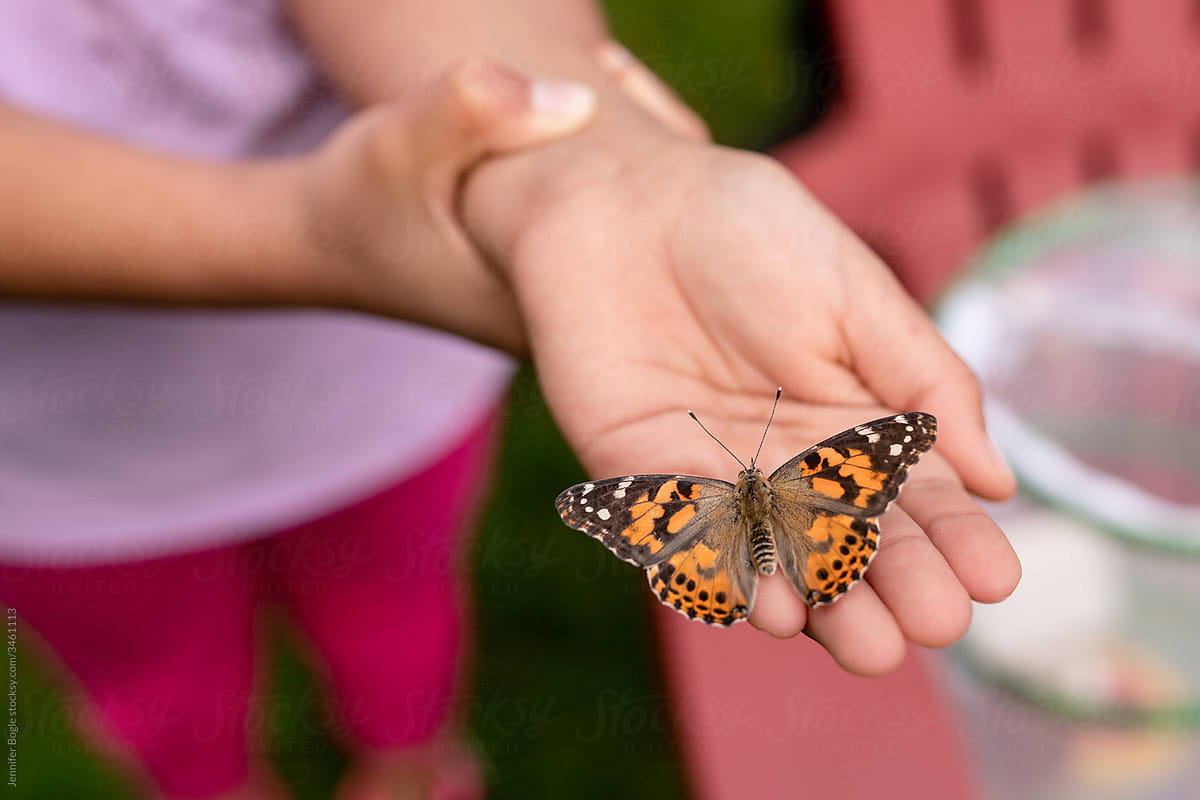 Girl holds butterfly on palm of hand