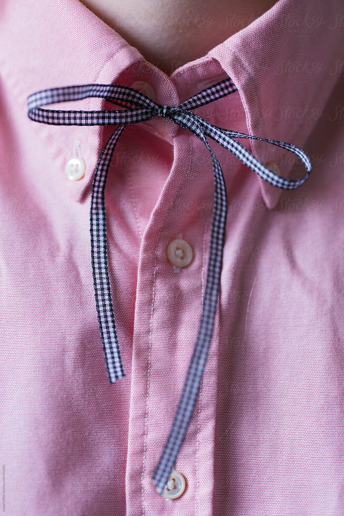 Close up of pink collared shirt with a blue ribbon tie