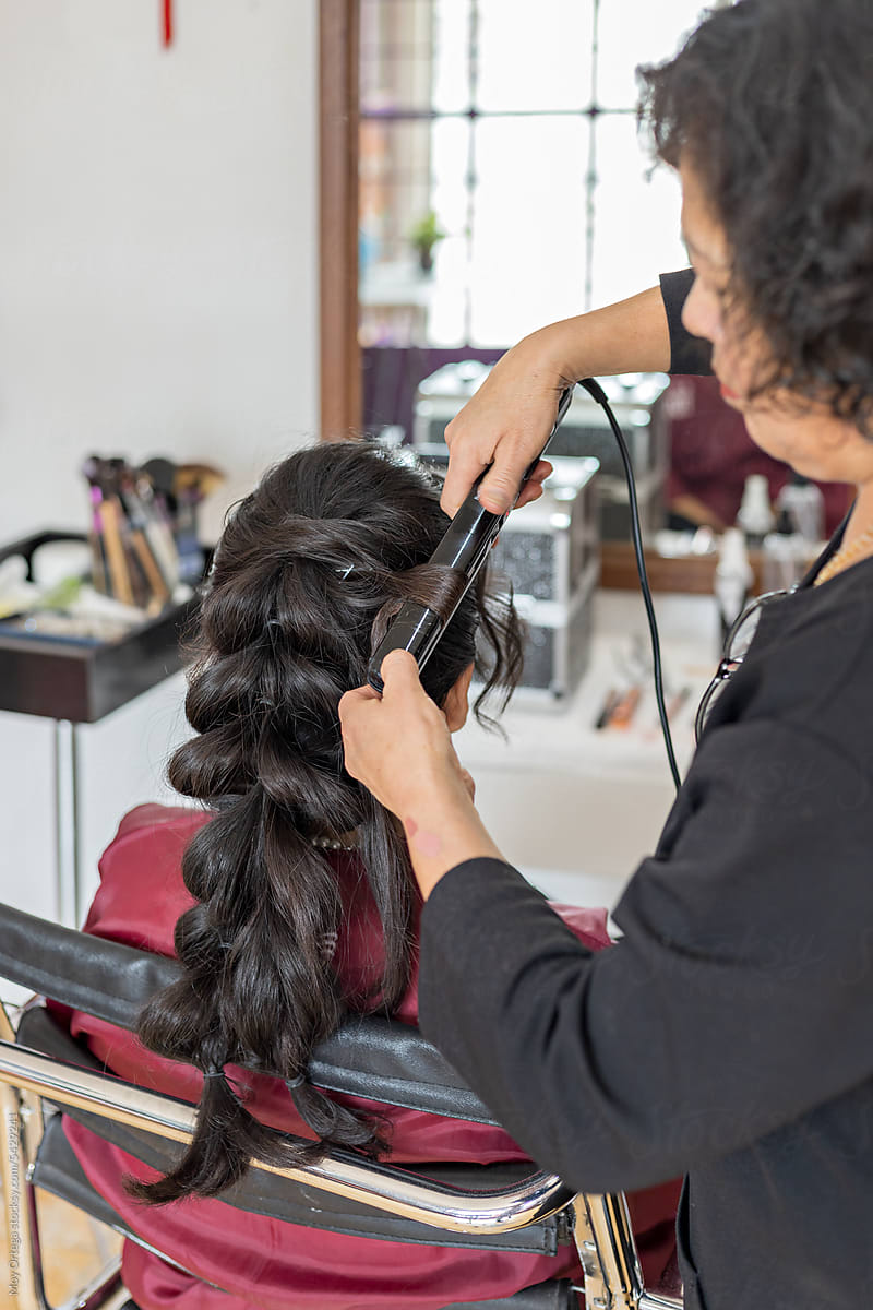 A Stylist Uses A Curling Iron To Style A Quinceanera
