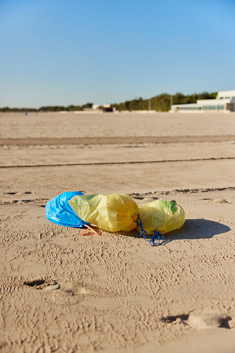 Plastic bags with litter on sand