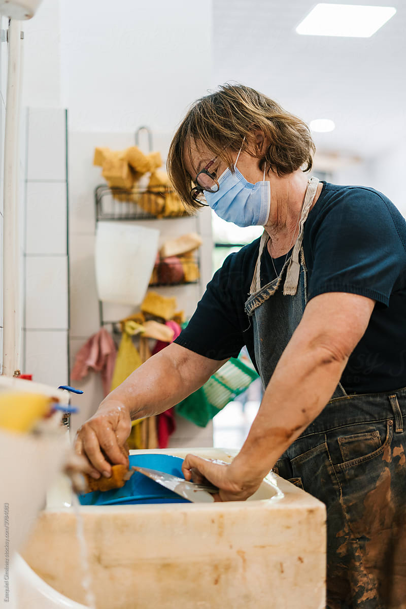 Woman mixing water with clay on a pottery vessel