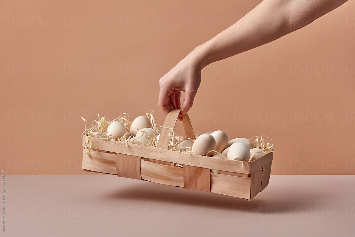 Wooden Easter eggs in eco basket held by woman.