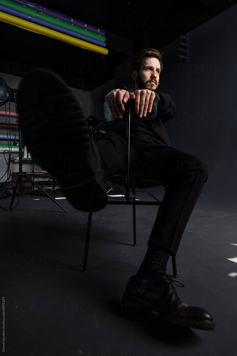 Man poses on chair in studio
