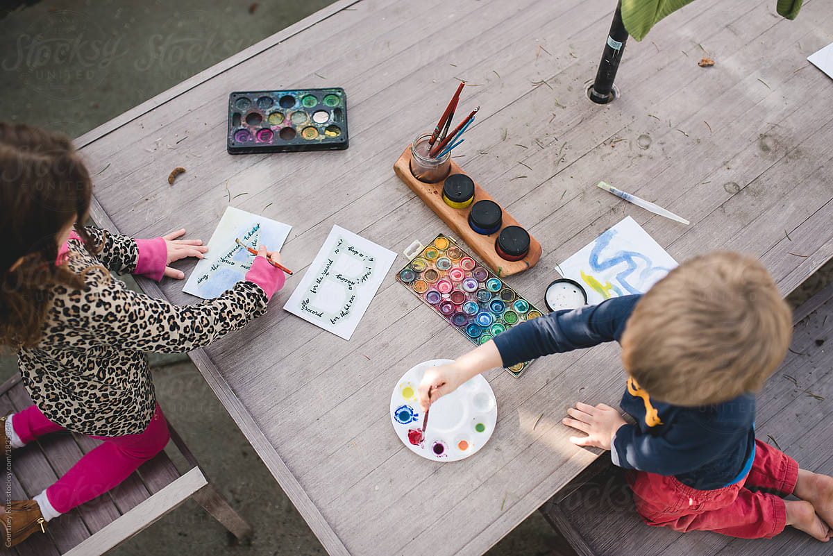 Overhead of children painting at an outdoor table