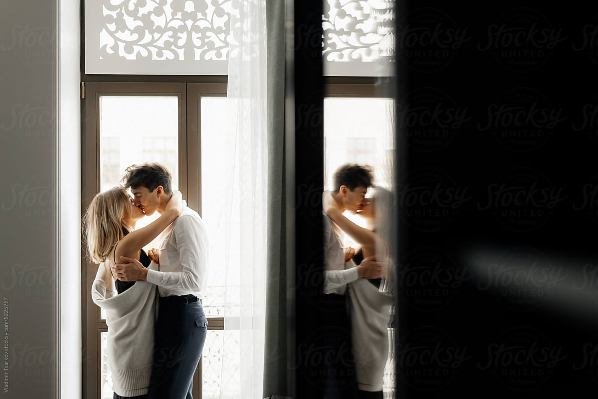 Couple kissing and hugging near window in hotel
