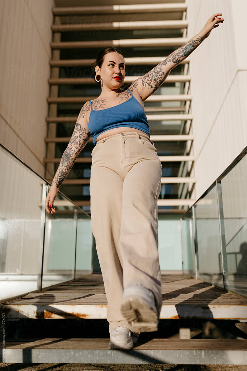 Tattooed plus size woman walking on stairs in city