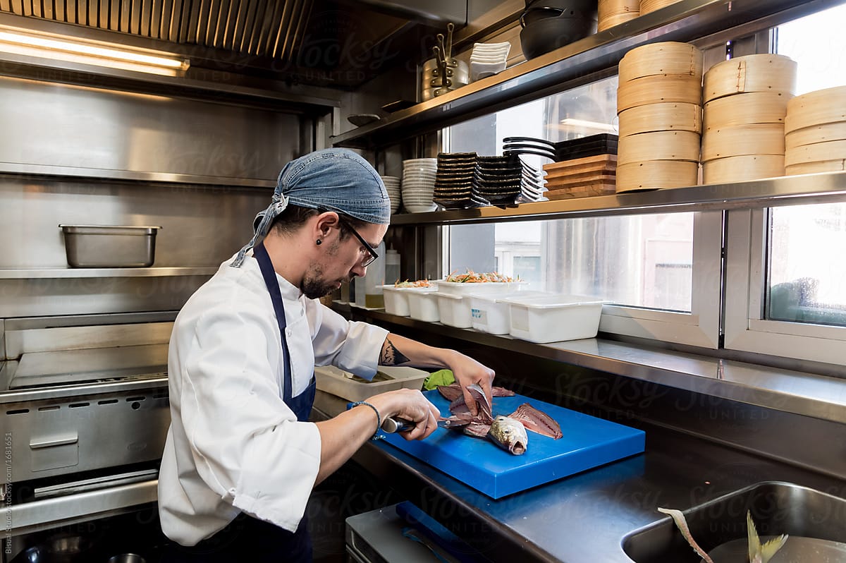 Man slicing raw fish at kitchen