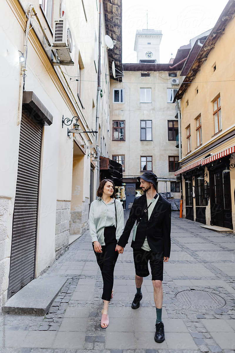 Fashionable couple strolling in lane surrounded by buildings