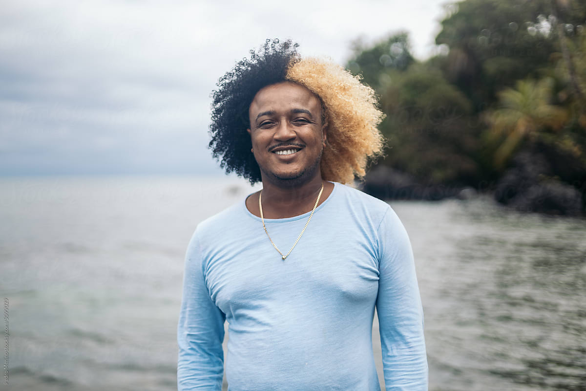 Portrait of a man with colored afro hair on the beach of an island