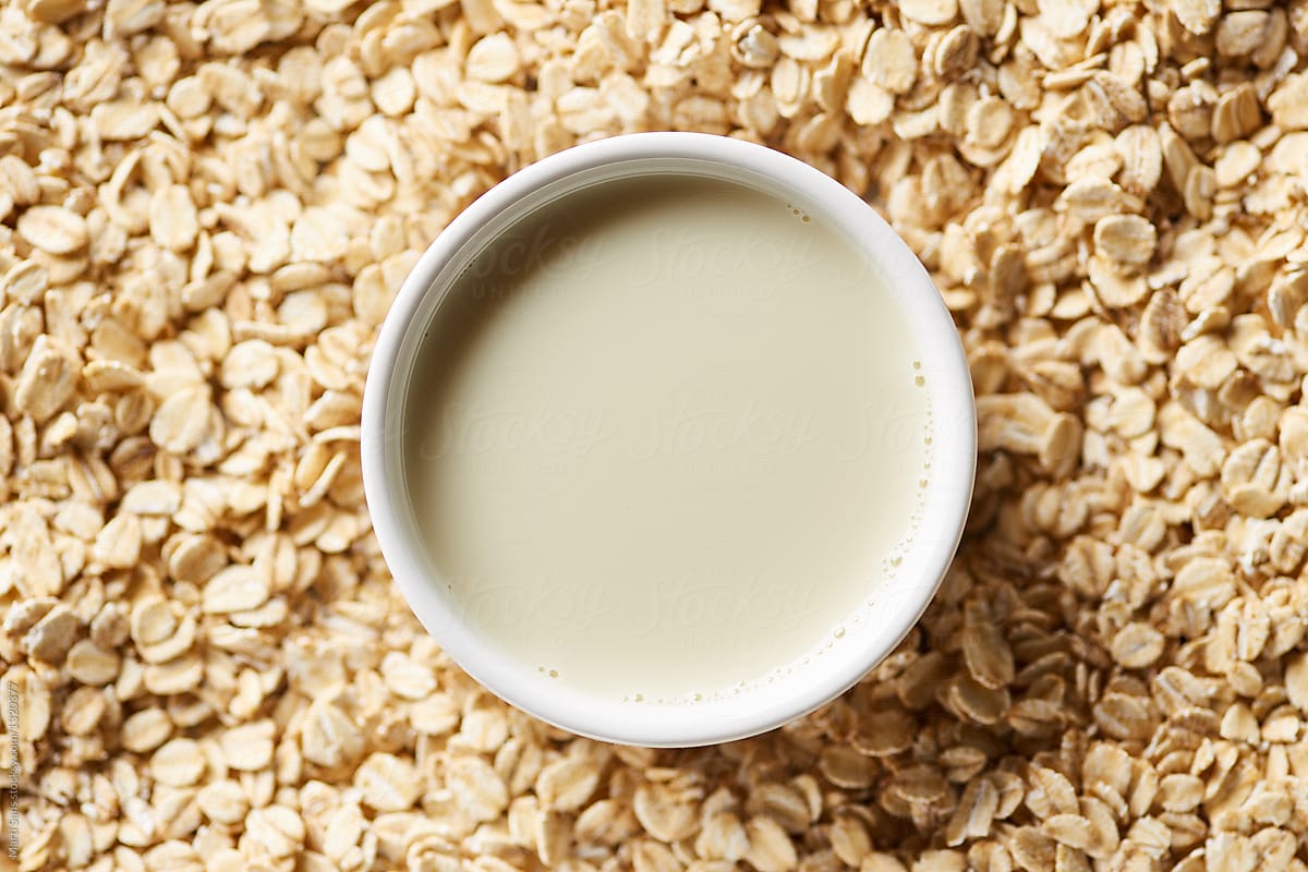 Non-dairy milk in bowl on oatmeal background.