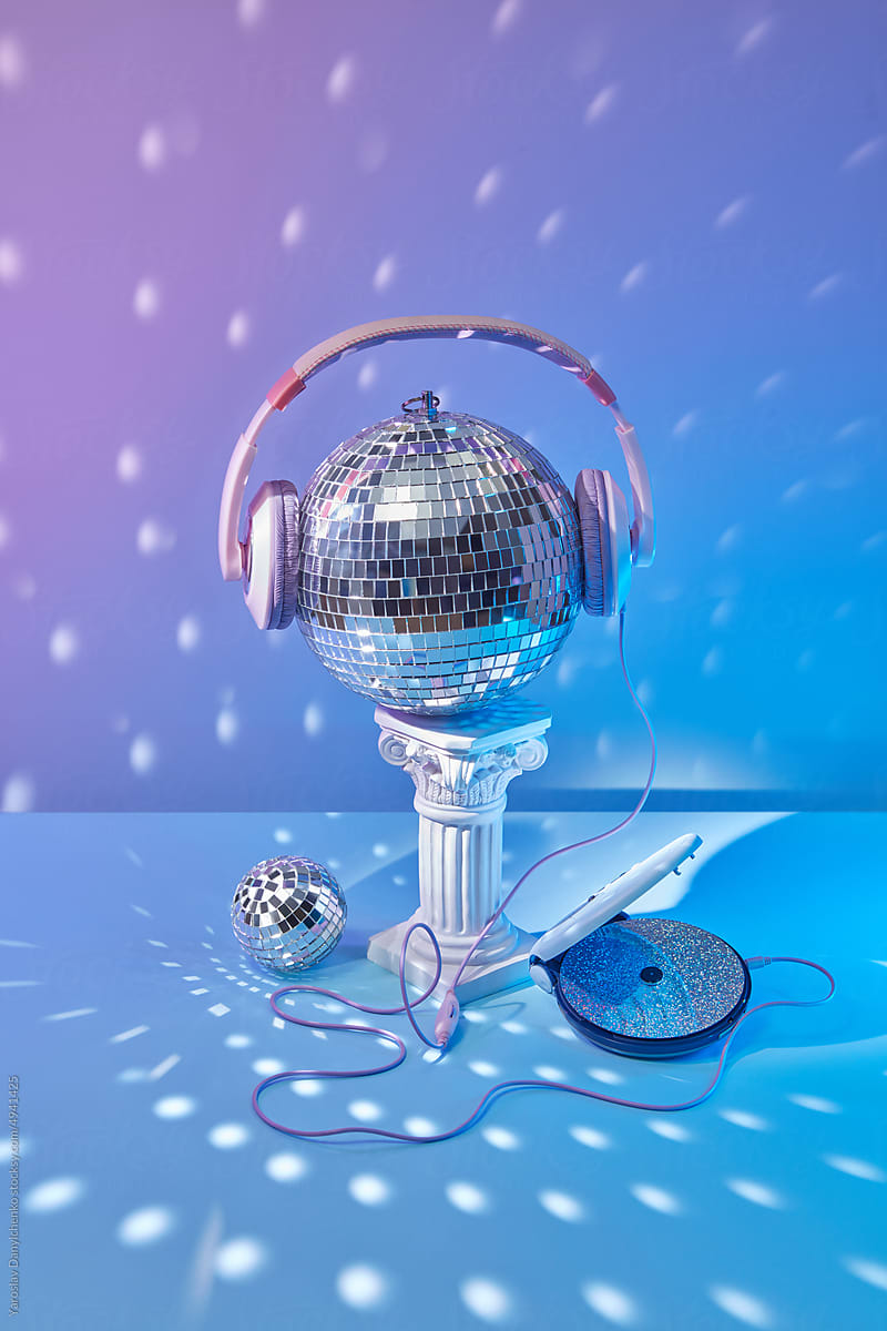 Headphones on disco ball, connected to CD player.