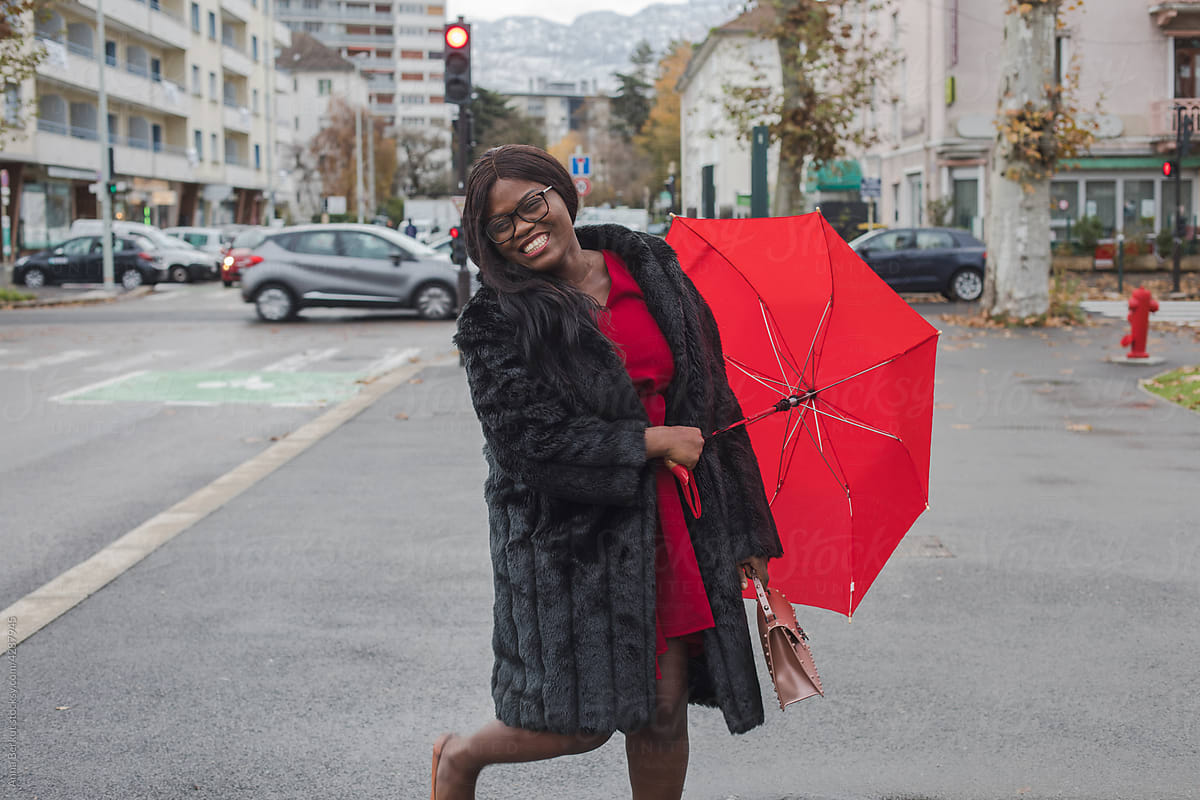 laughing woman wearing fur coat with red umbrella in the city