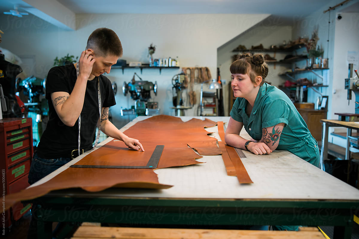 Two leather workers looking at a tanned hide.