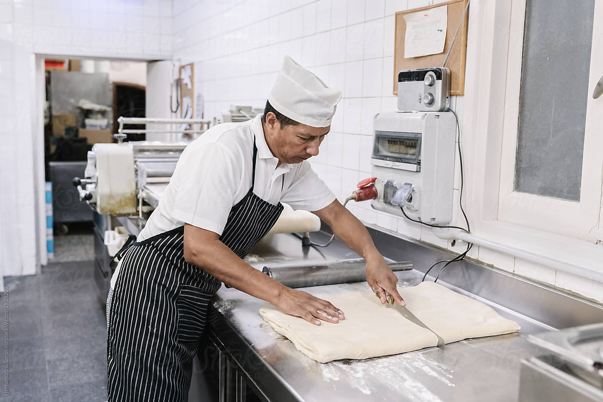 Professional Bakery Worker Cutting Dough