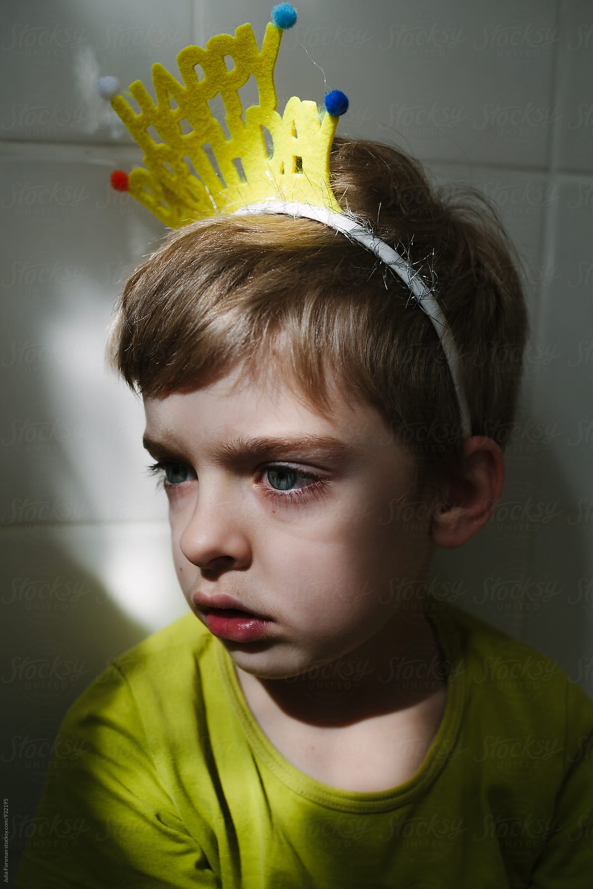 Close up of sad birthday boy sitting in bathroom.