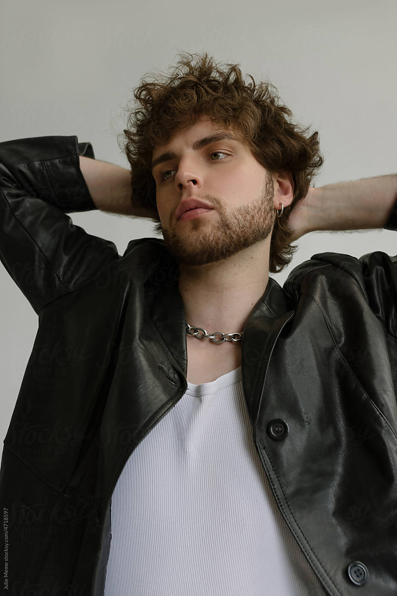 Bearded guy with curly hair in a  leather black coat and accessories