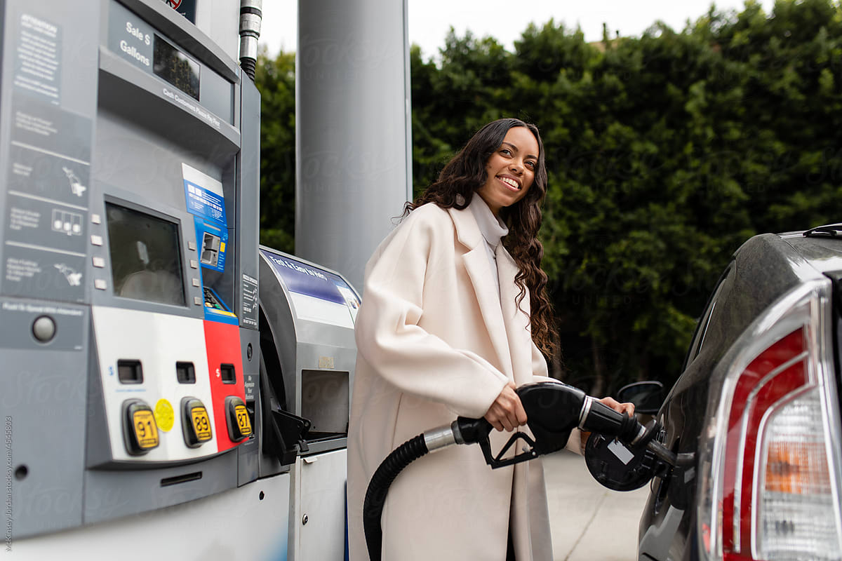 Young Woman Smiles As She Fills Her Vehicle With Gas