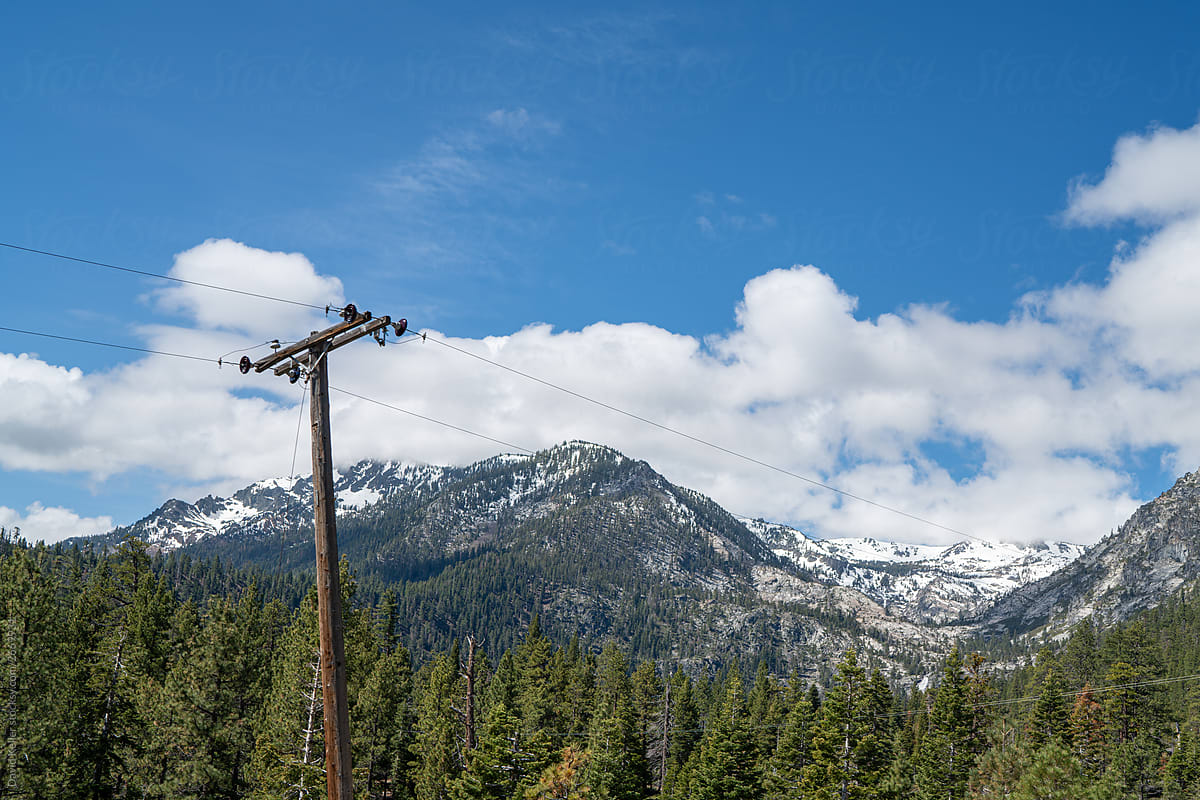 Snow capped mountains in the forest, with power lines in the foreground