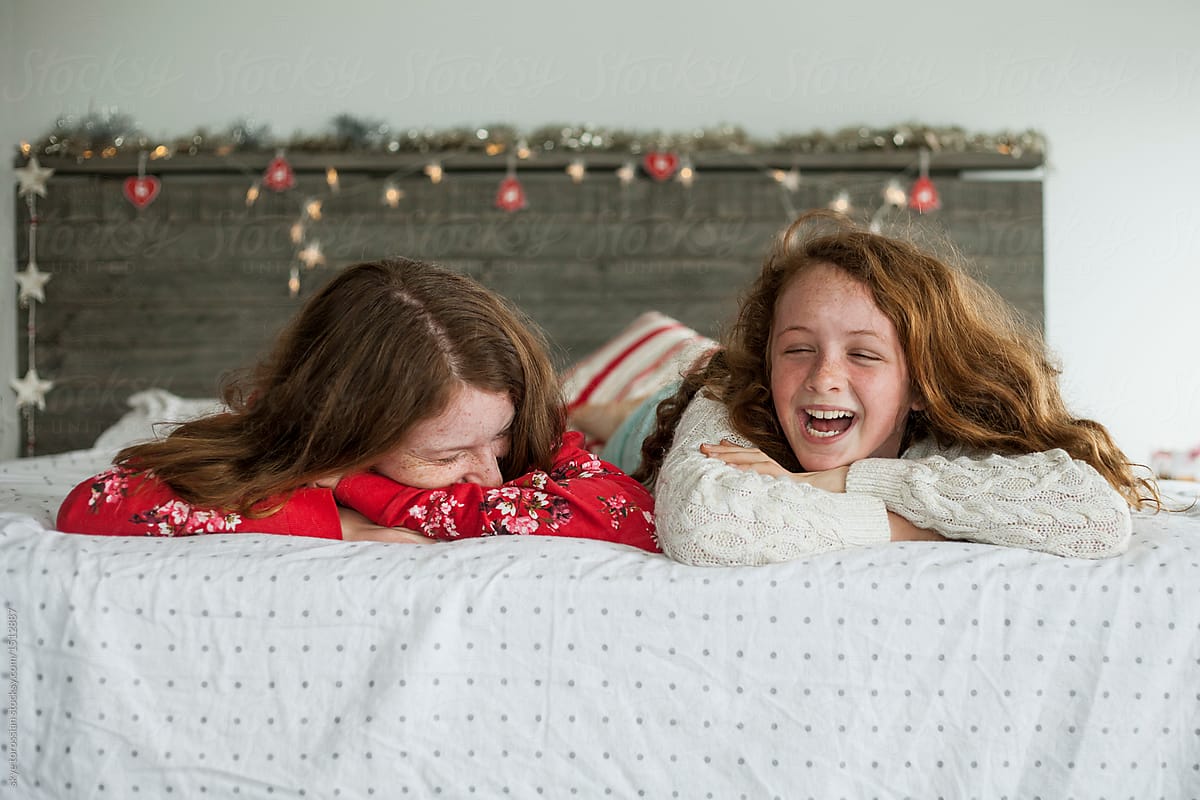 Sisters playing on bed with christmas decorations