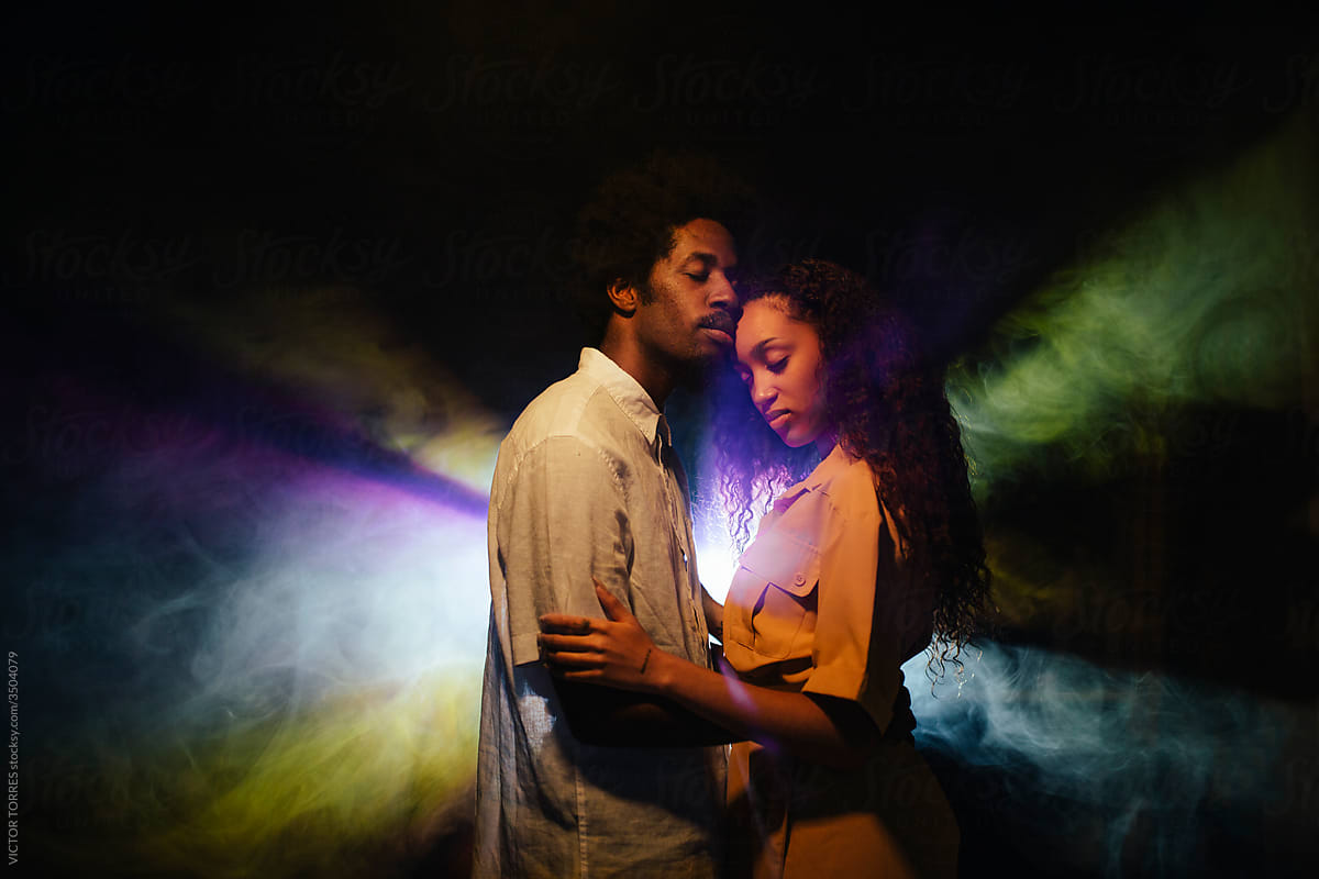 Loving black couple in studio with neon illumination