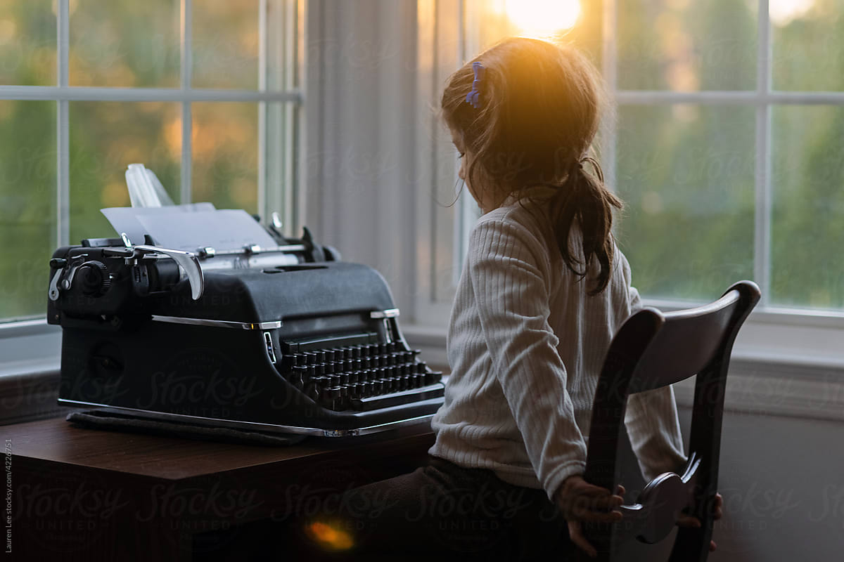 Little girl with typewriter by the window