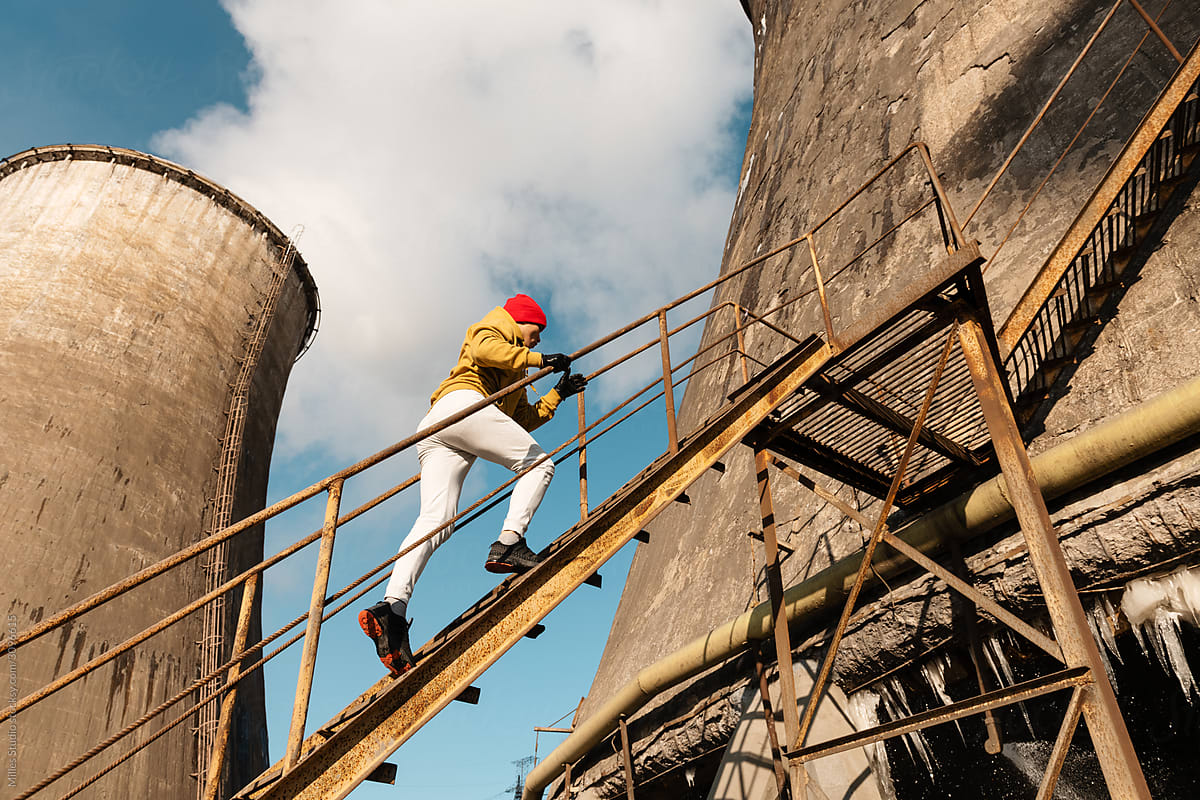 Male athlete running up rusty staircase of industrial plant